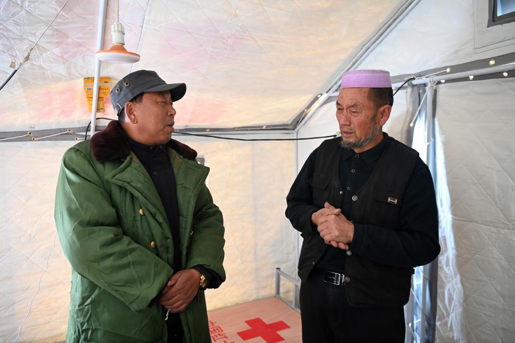 12月22日,在积石山县大河家镇克新民村,党支部书记张辉林(左)询问村民马辉文家安置情况。新华社记者 范培珅 摄