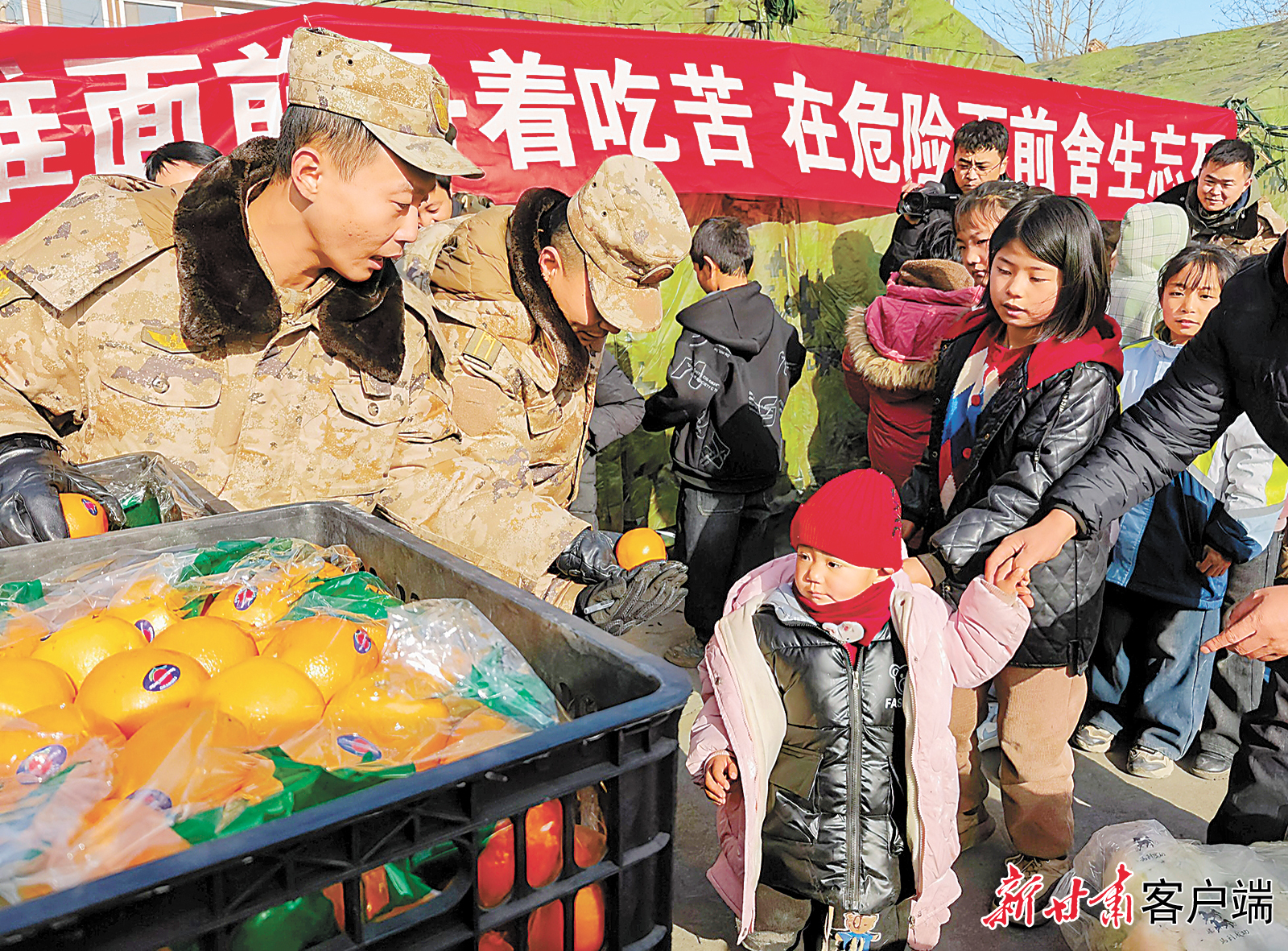 12月20日，西部战区陆军第76集团军某旅官兵在积石山县大河村临时安置点，为灾区群众分发水果。新甘肃·甘肃日报记者　郁婕