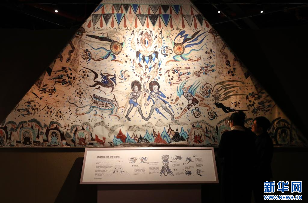 12月21日，参观者在莫高窟第285窟东披壁画（复制品）展品前交流讨论。