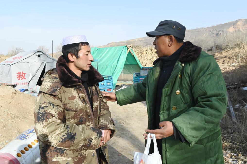 12月22日,在积石山县大河家镇克新民村,党支部书记张辉林(右)和米海成(左)商议安置事宜。新华社记者 范培珅 摄