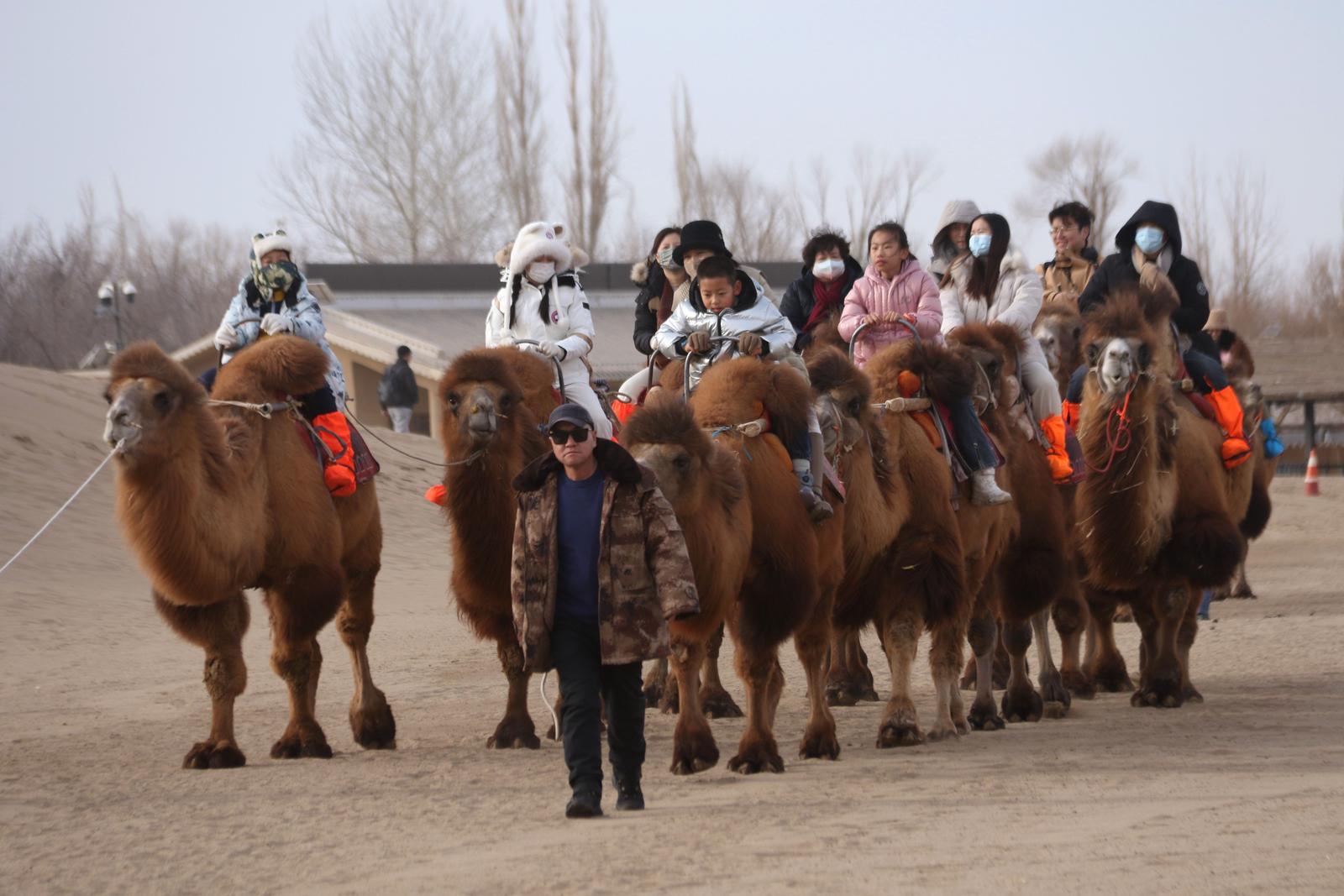 2023年12月31日，游客在甘肃省敦煌市鸣沙山月牙泉景区游览。