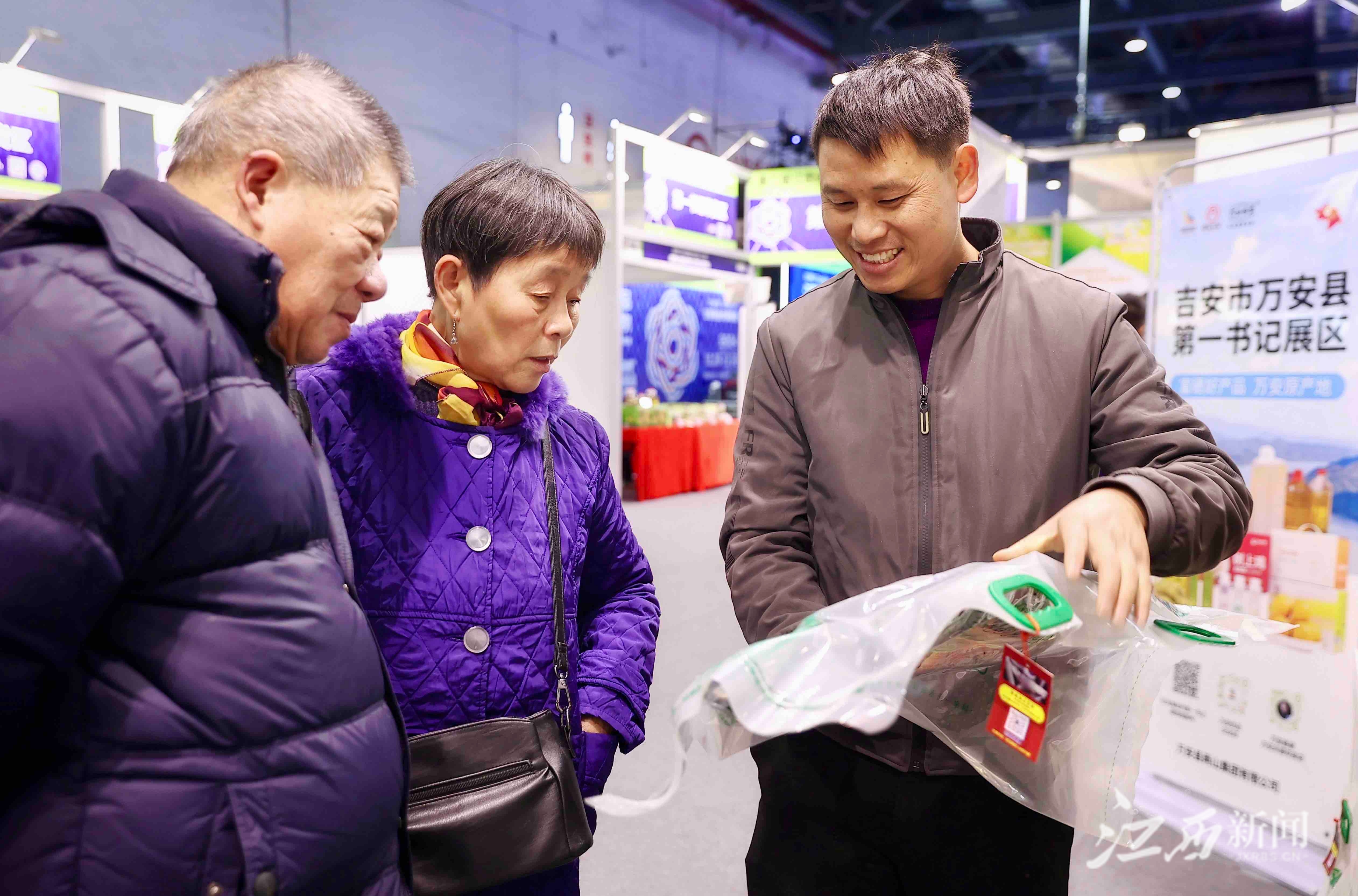 ▲来自万安增仚村的第一书记胡国权正向市民推介农家土特产品。