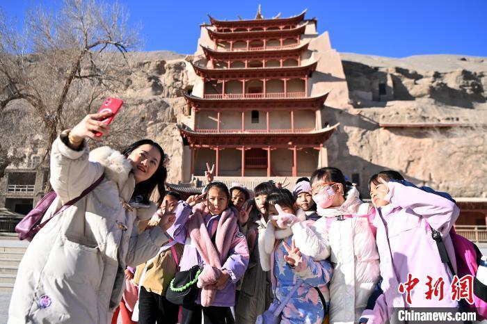 1月11日，来自青海中小学校的师生在敦煌莫高窟标志性建筑九层楼前合影留念。九美旦增　摄