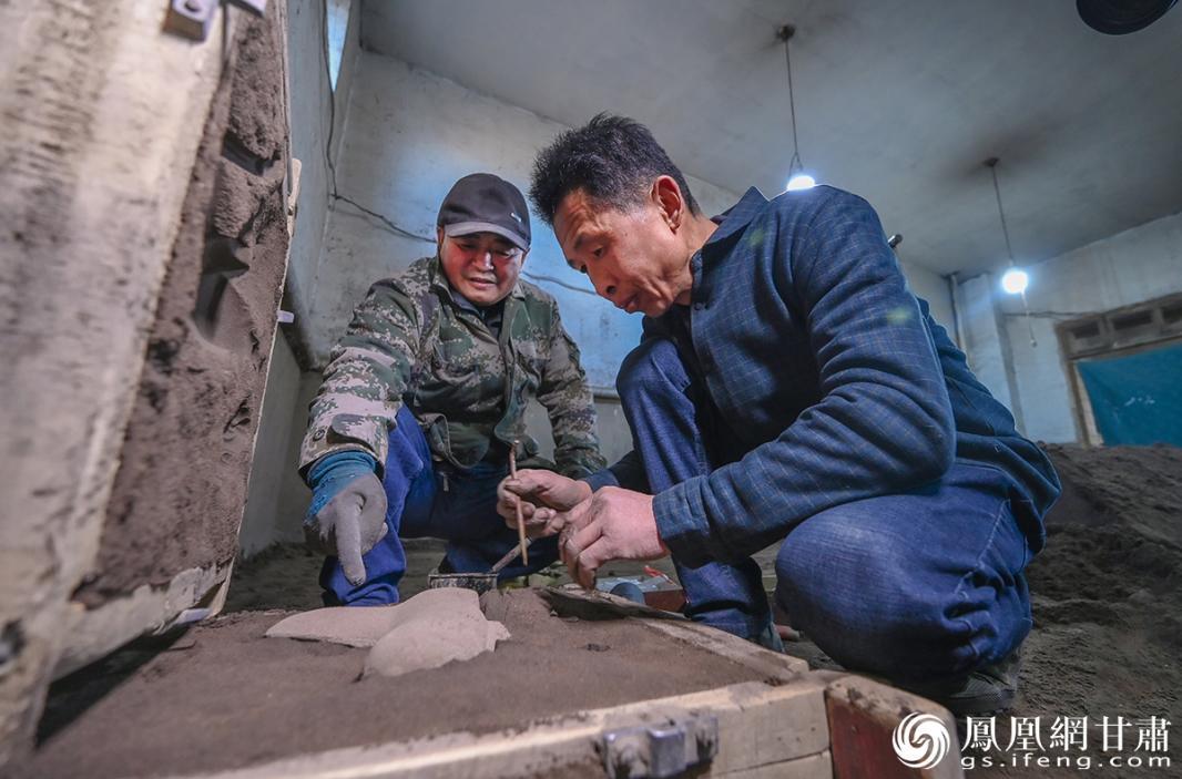 赵成（左）与匠人将完成造型的马身放入沙模中