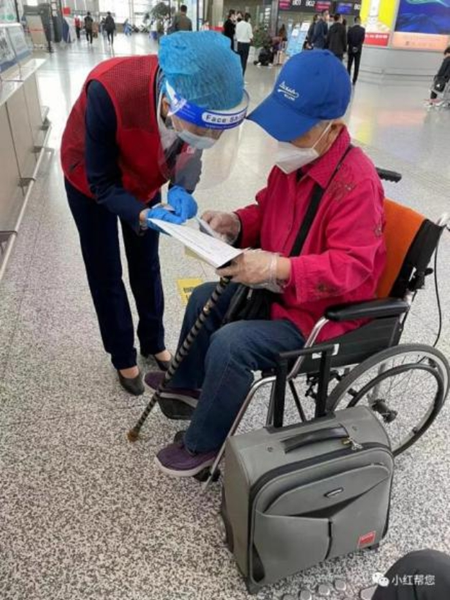 “小红帮您”正在帮助一位老年旅客