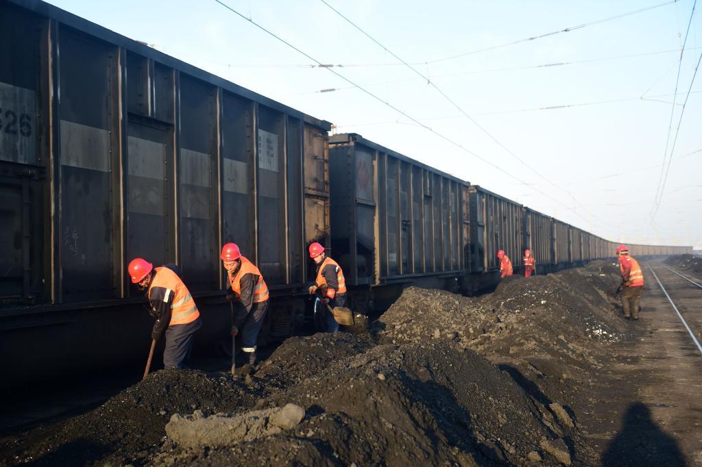 2023年12月25日，在河北黄骅港煤炭港区，清煤工正在整理车厢外的冻煤。新华社记者 王民 摄