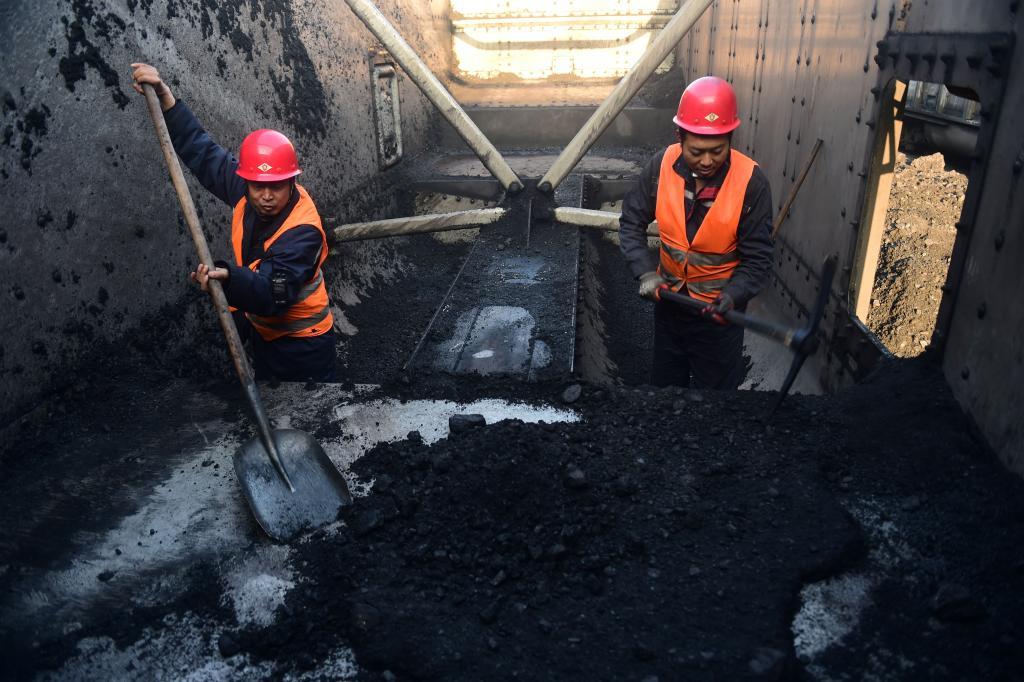 2023年12月25日，在河北黄骅港煤炭港区，清煤工正在清理车厢里的冻煤。新华社记者 王民 摄