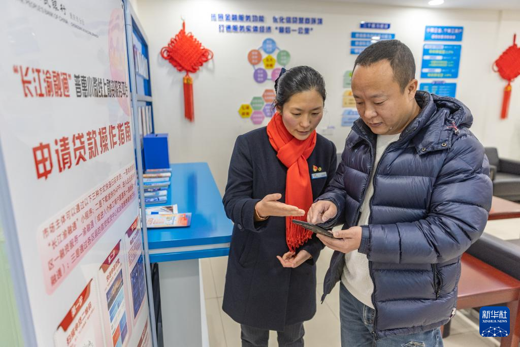 1月23日,在重庆市云阳县双江街道,中国建设银行云阳支行金融服务港湾工作人员指导前来咨询的商户通过线上融资服务平台申请贷款。