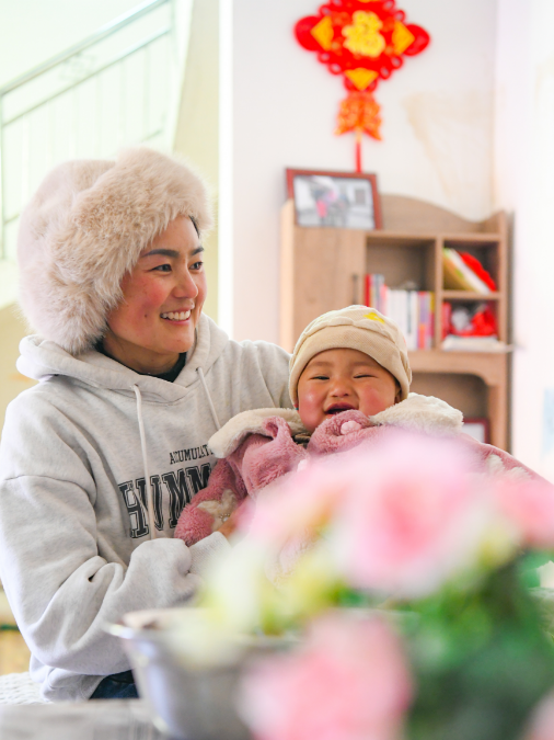 2月2日，巴木玉布木（左）抱着刚刚8个月大的小女儿王晓兰。新华社记者 王曦 摄