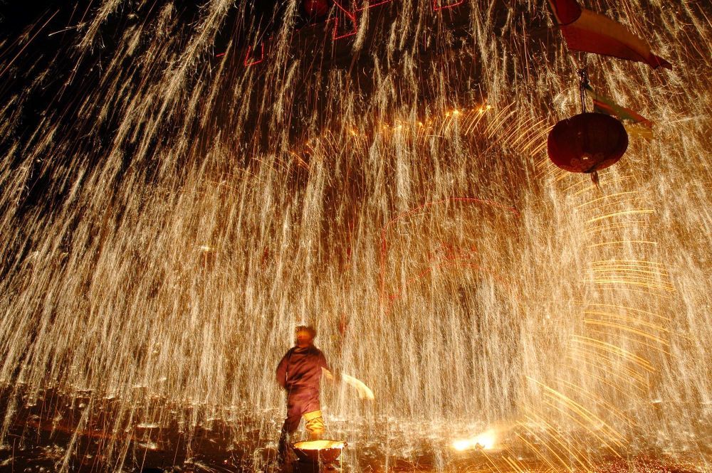 2006年元宵节前，一名“铁匠”在河北蔚县古城门前进行打树花社火表演。