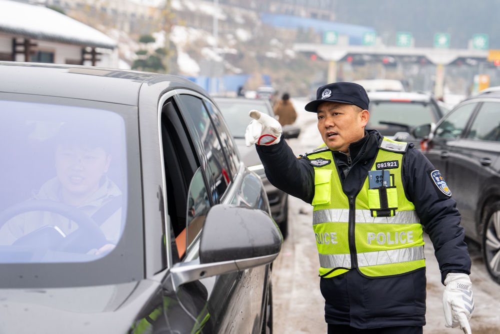 2月6日，在湖南长张高速慈利东收费站附近，交警解答滞留旅客的提问。新华社记者陈思汗摄