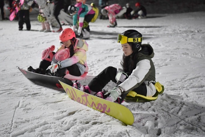 滑雪爱好者在鳌山滑雪场夜场中穿戴雪板。新华社记者邵瑞摄