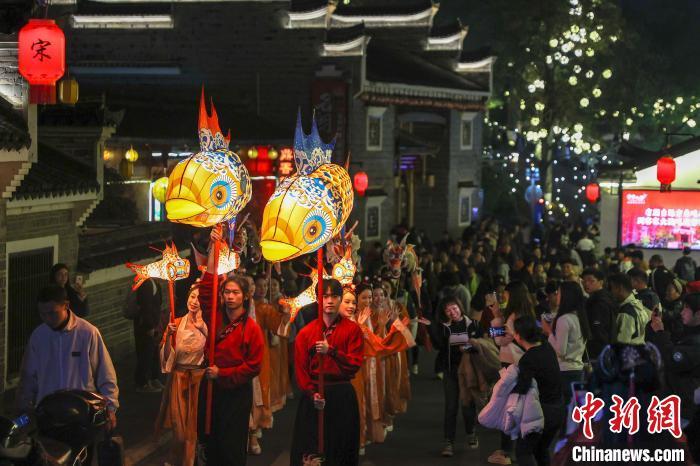 图为鱼灯夜游队伍行走在古街区内，众多游客在一旁拍照“打卡”。刘力鑫 摄