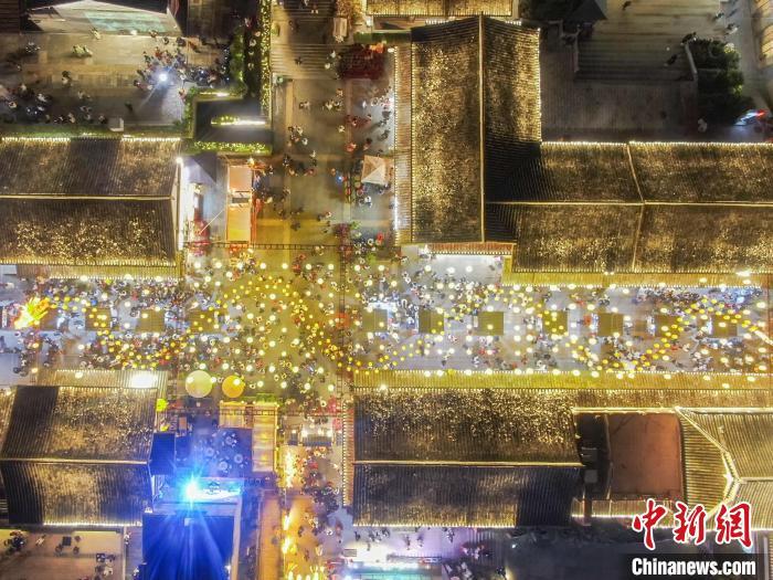 图为航拍古街区灯火璀璨，一个长龙造型花灯被悬挂在空中，众多游客在观光游览。刘力鑫 摄