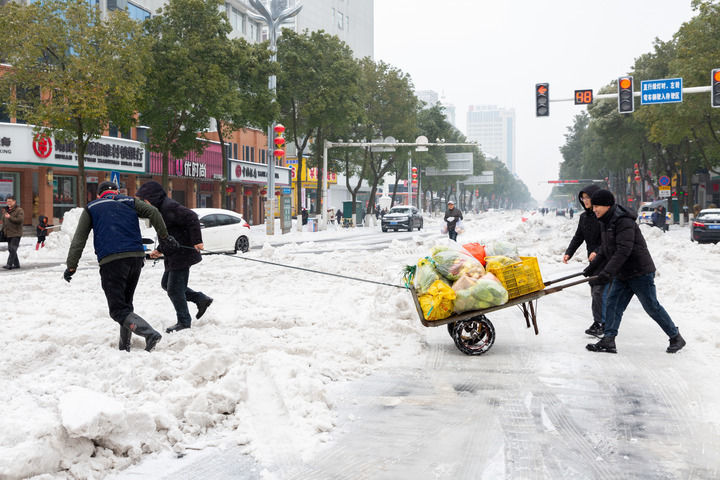 2月4日，在湖南省常德市桃源县漳江街道，志愿者用人力推车为社区居民送去蔬菜。新华社发（黄群摄）