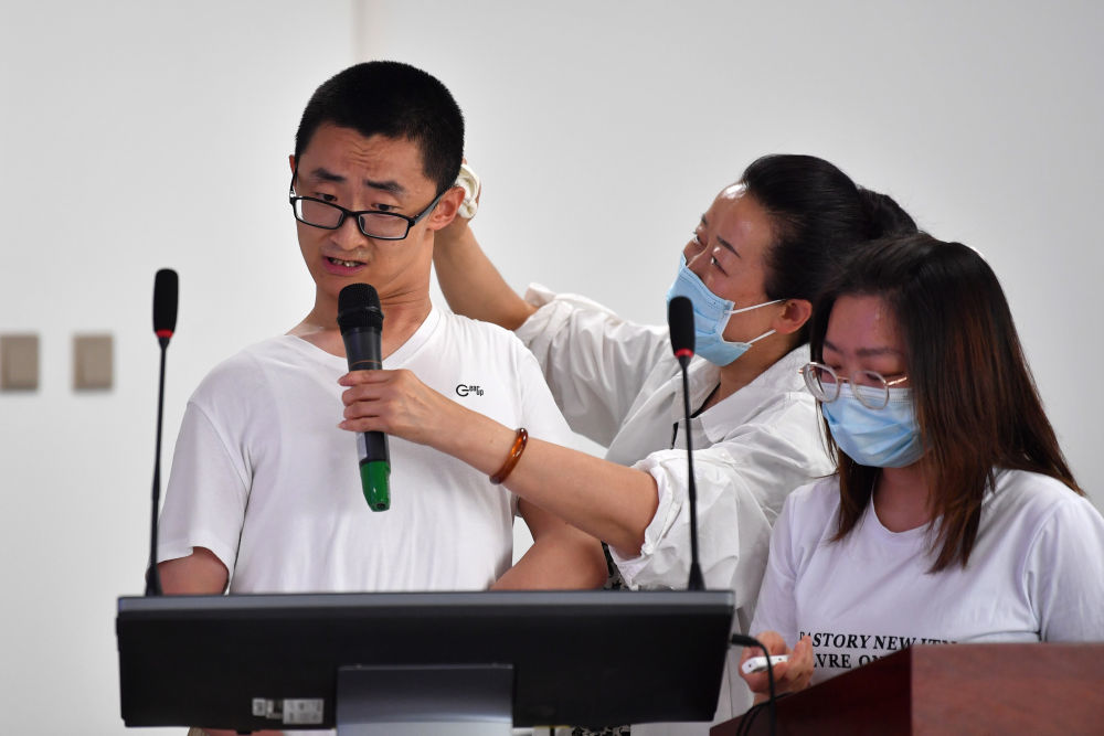 2023年5月24日，谢炎廷（左）在兰州大学数学与统计学院进行论文答辩，母亲刘小凤（中）在一旁为他擦汗。新华社记者　陈斌　摄