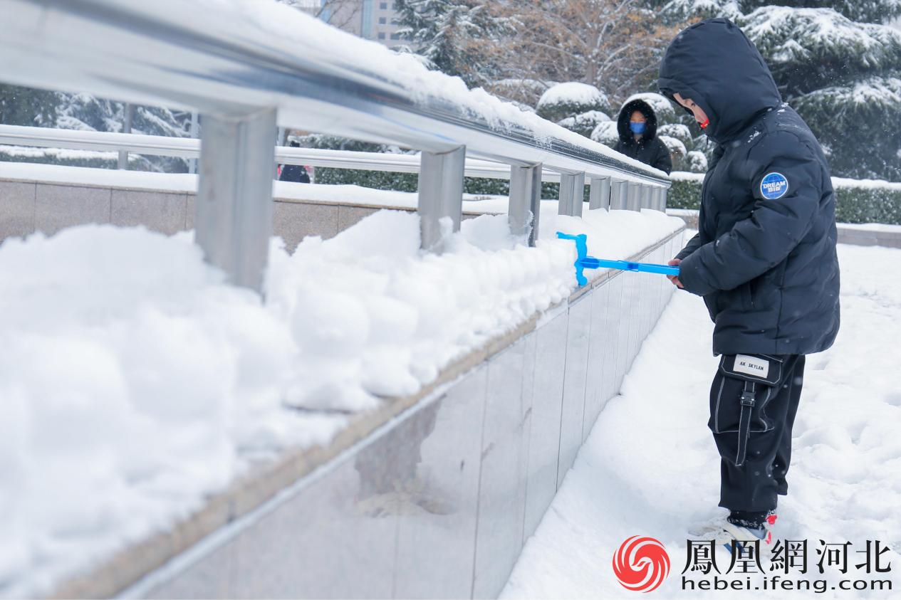 布满积雪的护栏边，小男孩用模具按压出一个个可爱的“小熊雪球”。
