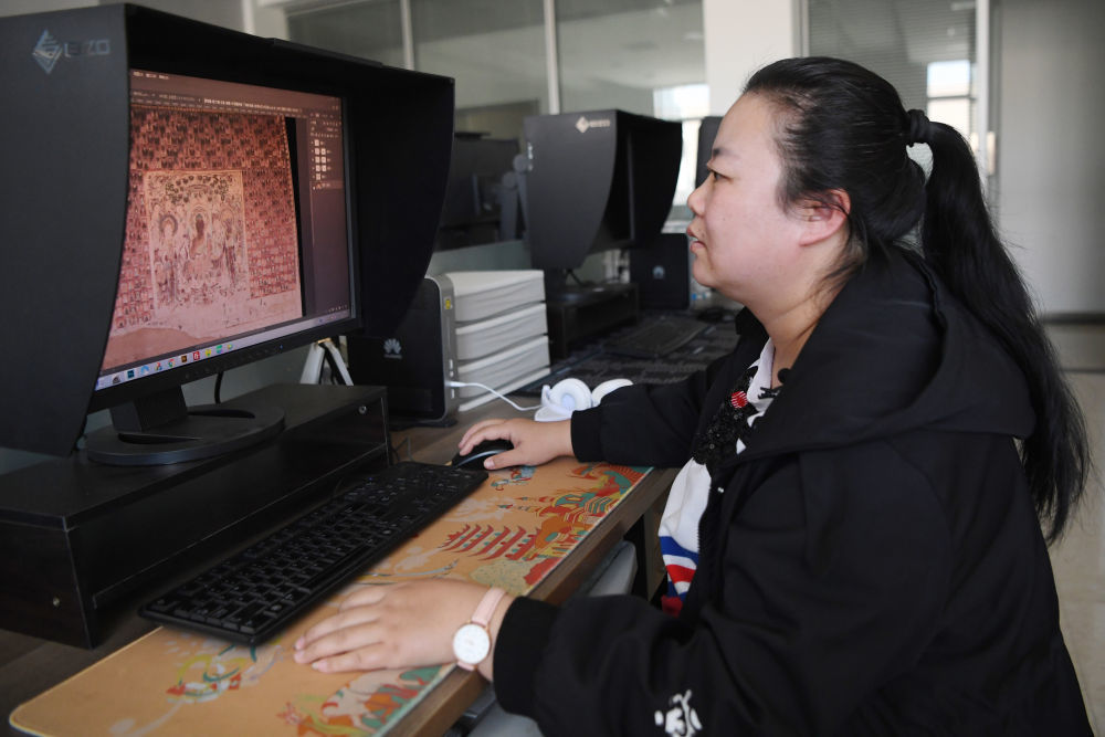 敦煌研究院文物数字化保护团队图像处理人员年海丽在拼接壁画图像（2023年4月25日摄）