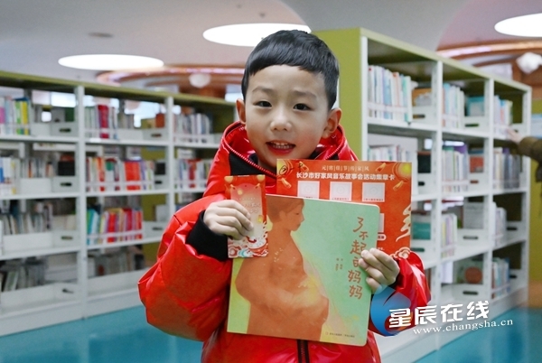 （在“你找书、我买单”环节中，一位小朋友成功找到夹有活动主题书签的书籍，笑着向记者展示。）