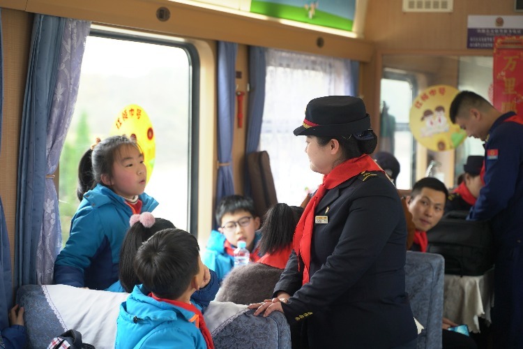 “红领巾号”列车流动课堂上，党的二十大代表、南昌火车站客运值班员李军和少先队员们问答互动。（谢天 摄）