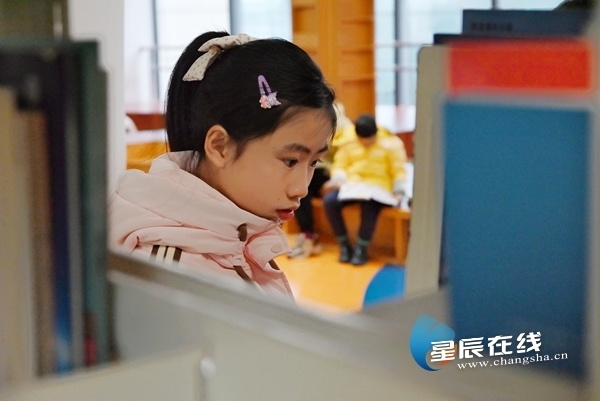 （在图书馆三楼，小朋友们正在寻找夹有活动主题书签的书籍。）