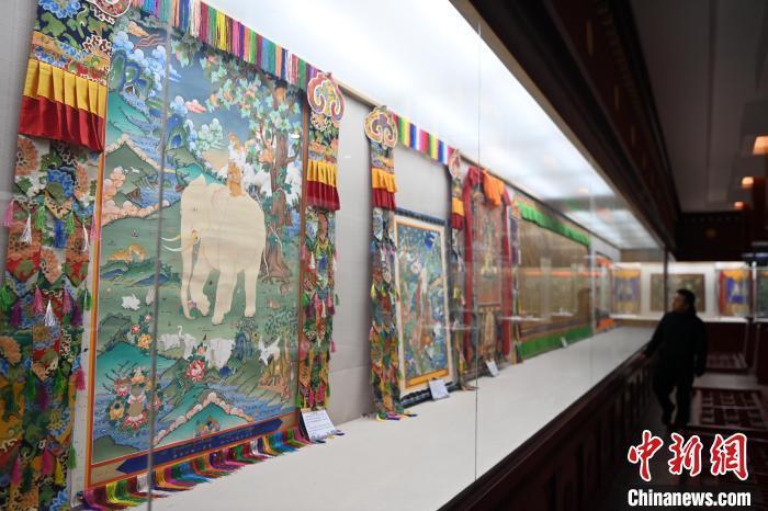 距离唐卡小镇数十米远的精品唐卡展厅，摆满了甘南藏族唐卡国家级代表性传承人交巴加布与父亲二人的作品。图为交巴加布与父亲的唐卡作品吸引游人“打卡”。九美旦增 摄