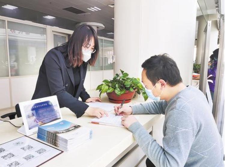 2023年2月27日，在沧州市行政审批局企业开办专区，工作人员（左）指导办事人员准备营业执照变更业务的相关材料。河北日报 资料图