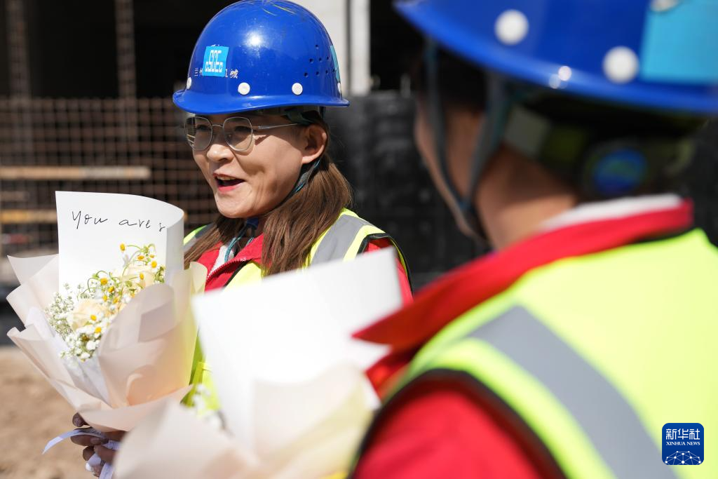 3月6日，在中建三局兰州大学榆中校区项目建设工地，王甜甜（左）和搭档的信号工袁婷婷收到单位送的妇女节鲜花。