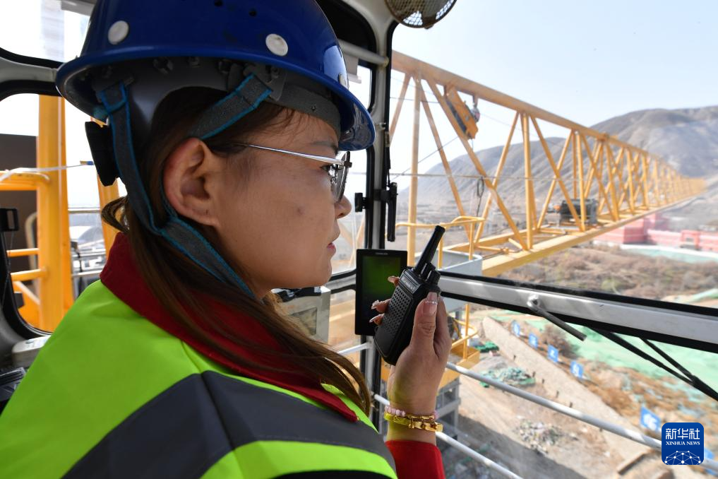 3月6日，在中建三局兰州大学榆中校区项目建设工地，王甜甜在塔吊驾驶室内用对讲机和地面信号工沟通。