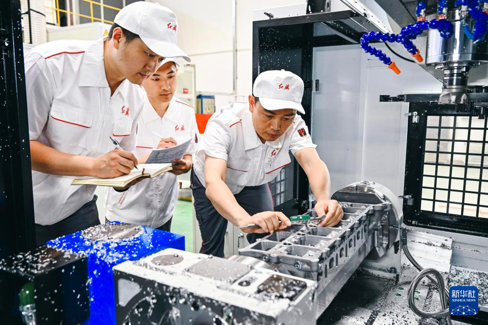杨永修（右）在中国一汽研发总院加工车间内检查试制零部件的精度（2023年6月8日摄）。新华社记者 许畅 摄