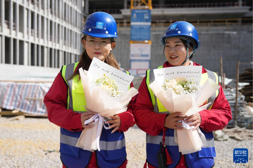 3月6日，在中建三局兰州大学榆中校区项目建设工地，王甜甜（左）和搭档的信号工袁婷婷收到单位送的妇女节鲜花。