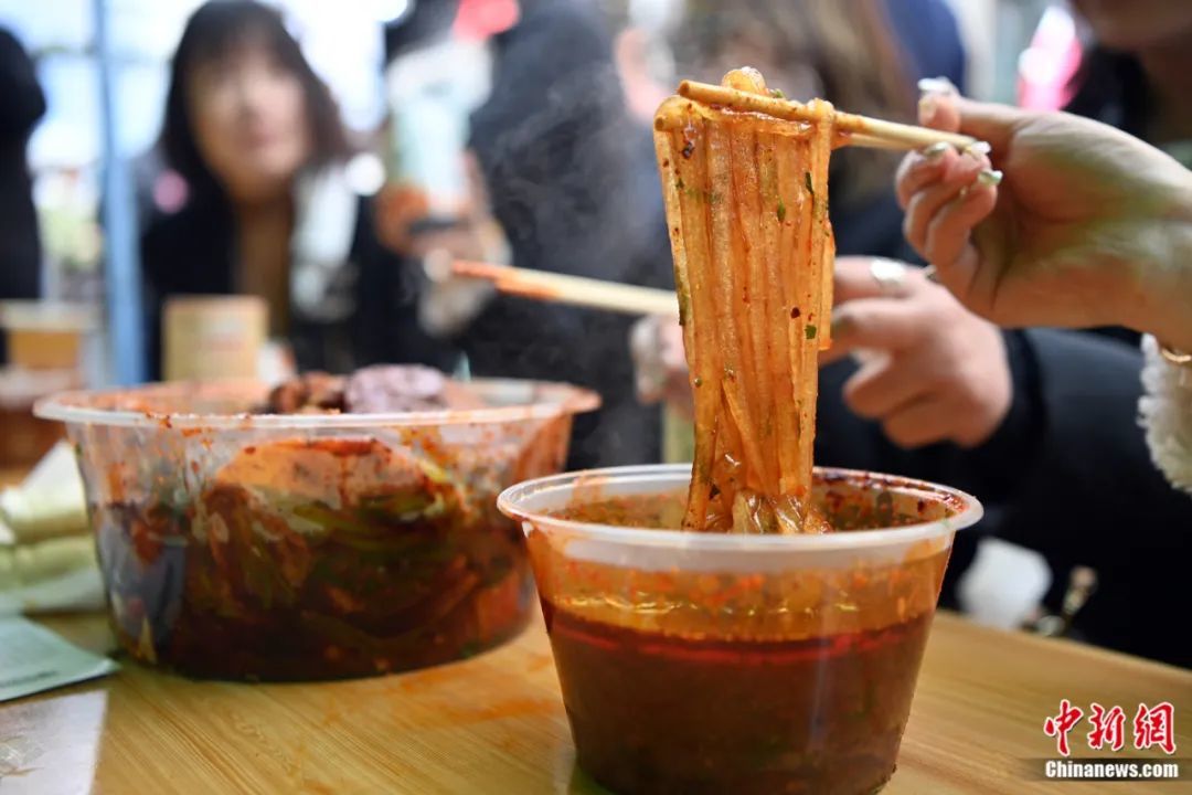 3月14日,甘肃天水,游客正在品尝麻辣烫。劲道爽滑的粉条是食客们最为推荐的。九美旦增 摄