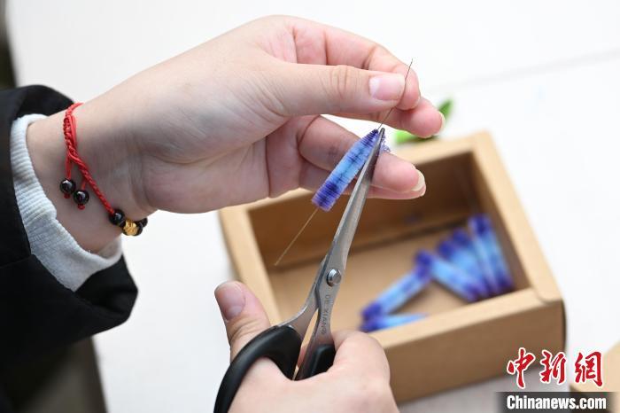 在老师的指导下，一朵朵姹紫嫣红的绒花在指尖“绽放”，与一旁的梅花相映成趣。泱波 摄