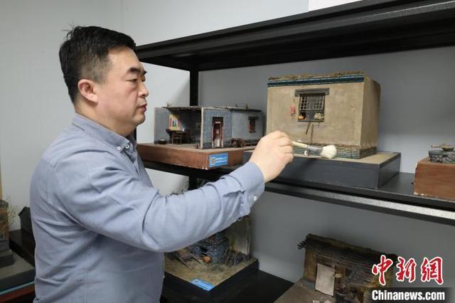 图为王伟为老式民居微缩景观模型清理浮尘。徐鹏璐 摄