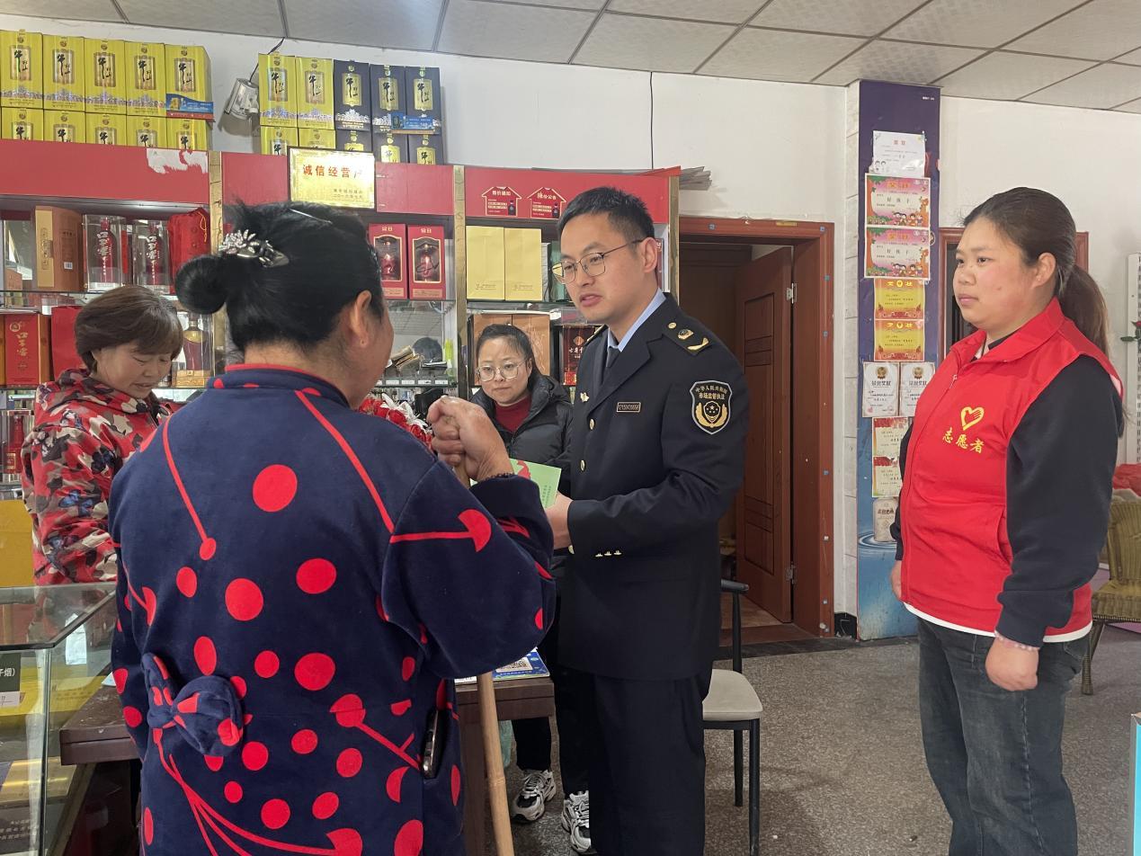 图为：市场监管行政执法人员和志愿者们向村民宣传禁毒知识