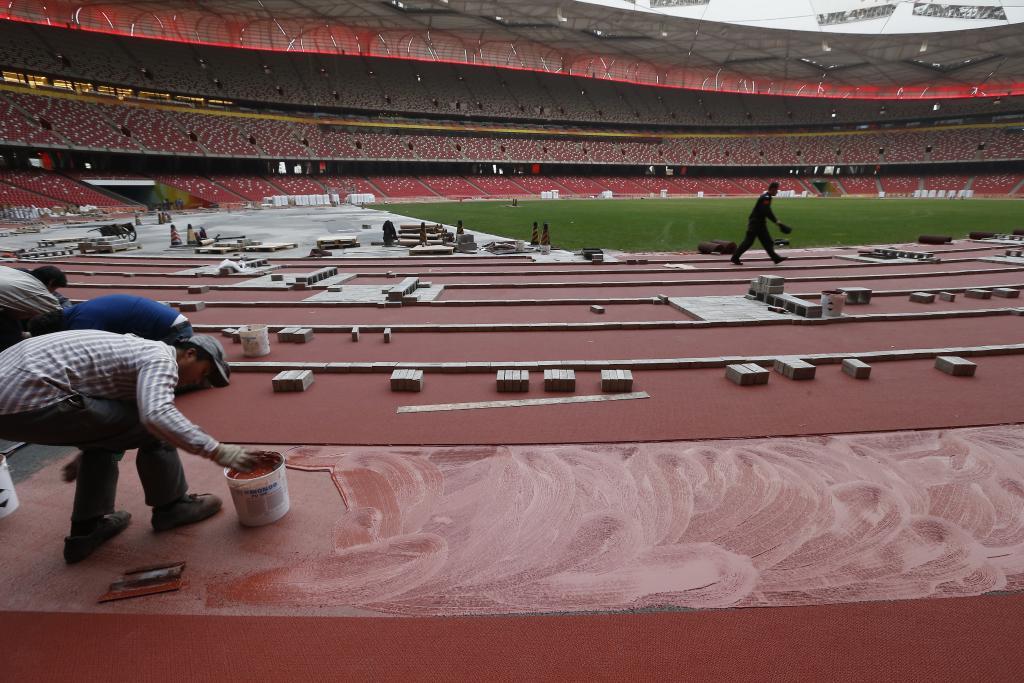 资料图：2015年3月29日，工作人员在“鸟巢”铺设专业预制塑胶跑道，为当年在北京举行的田径世锦赛做准备。新华社发