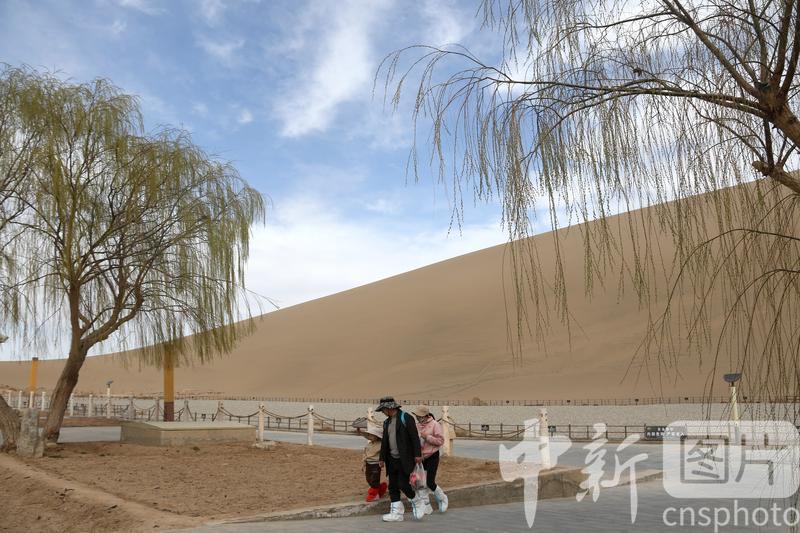 2024年3月24日,游客在甘肃省敦煌市鸣沙山月牙泉景区游览。中新社发 张晓亮 摄