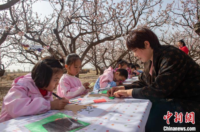 3月29日，幼儿园老师正在杏花林里带领小朋友们制作手工艺品。李金刚摄
