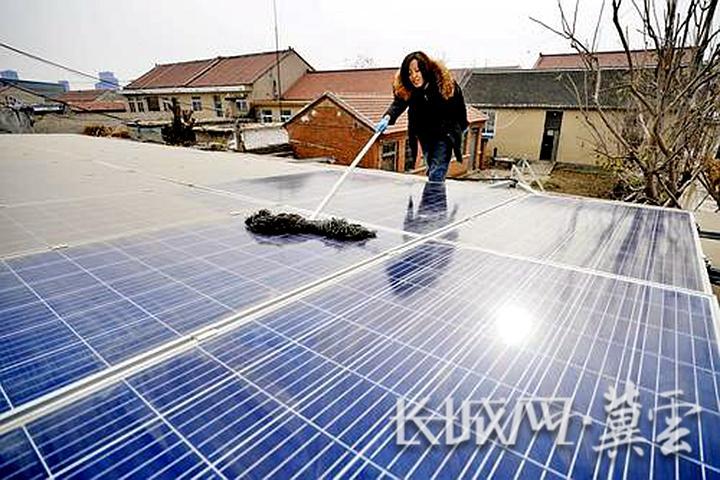 玉田县林头屯乡东芦庄村村民在清洁自家房顶的光伏发电板。新华社发
