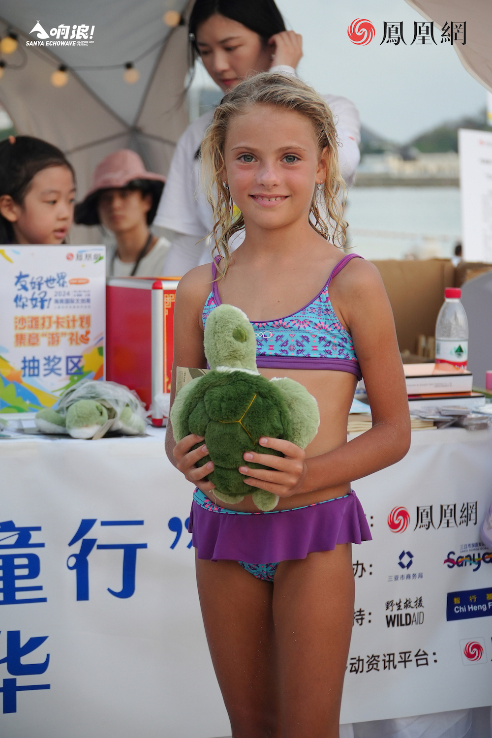 俄罗斯小女孩作为传播小志愿者参与凤凰网“美丽童行”公益嘉年华摊位的海洋环保互动游戏。