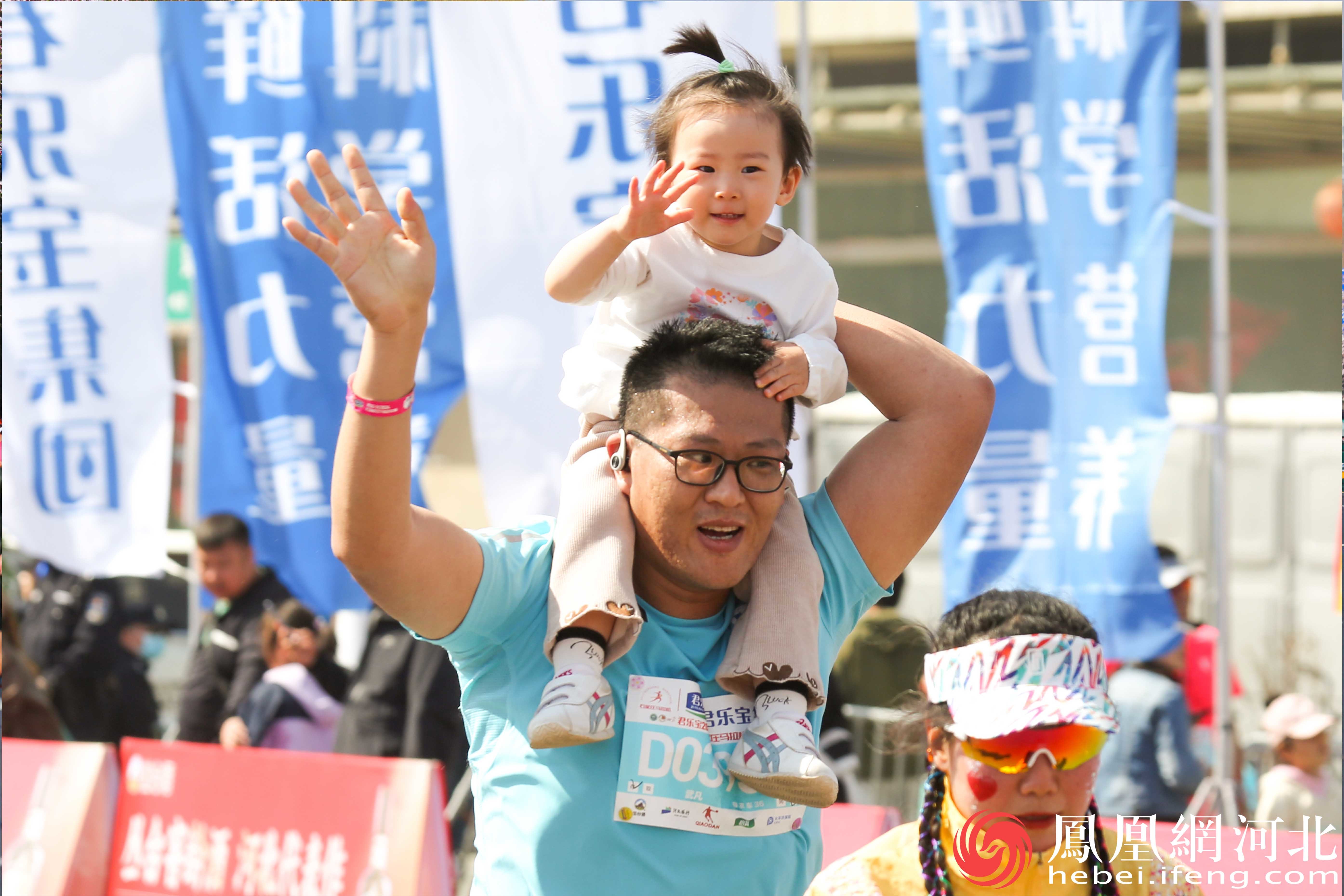 在马拉松赛道上，一位父亲背着女儿奔跑着，孩子脸上洋溢着幸福的微笑。