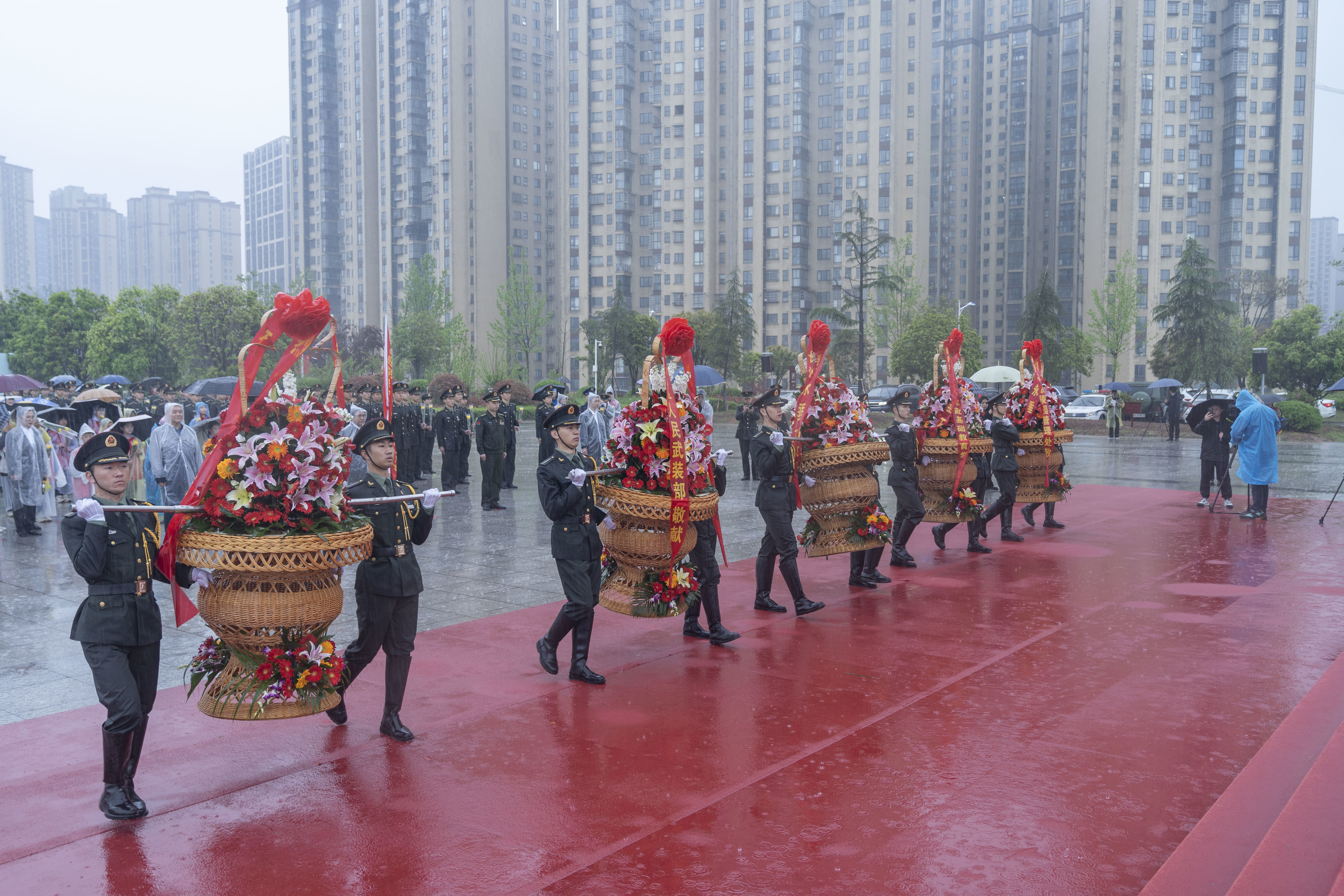 礼兵抬起花篮，正步走向英烈纪念碑。