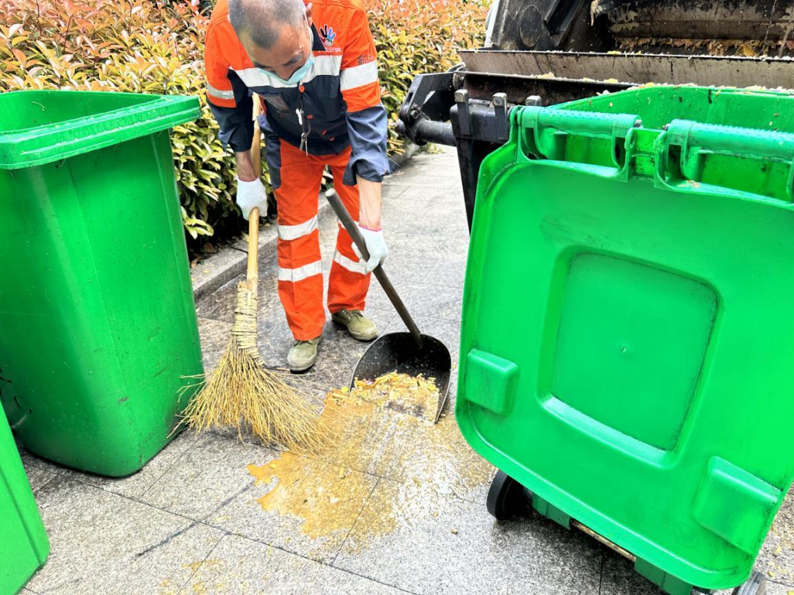 戴好手套和口罩,合力将满满的餐厨垃圾桶抬至厨余车内并进行倾倒