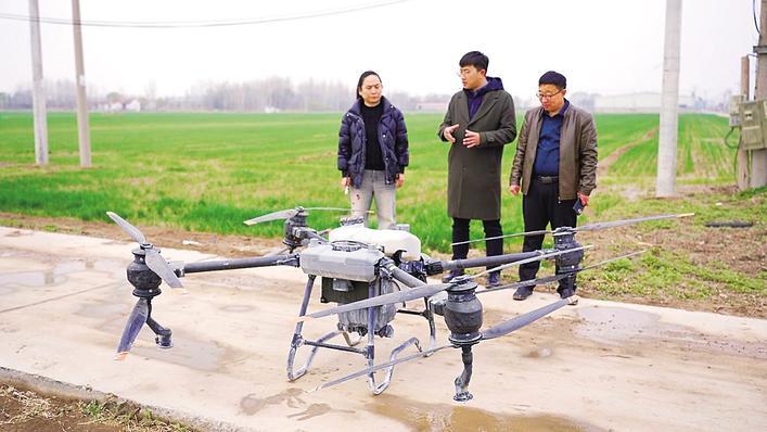 技术人员向种植户王晓玲（左一）讲解无人机喷洒药液知识