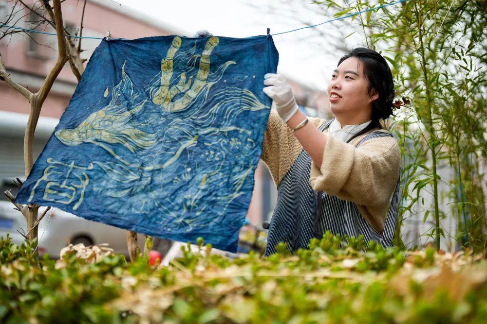 ↑4月6日,李萨在整理上色后的蜡染作品。
