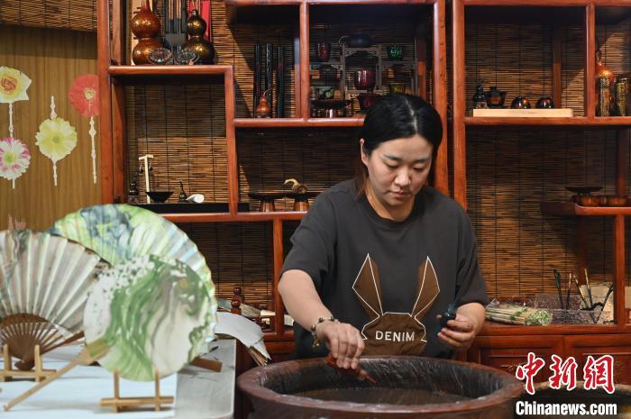 4月18日,漂漆扇制作,张曼瑜向水中滴入调制好的色漆。张俊杰 摄
