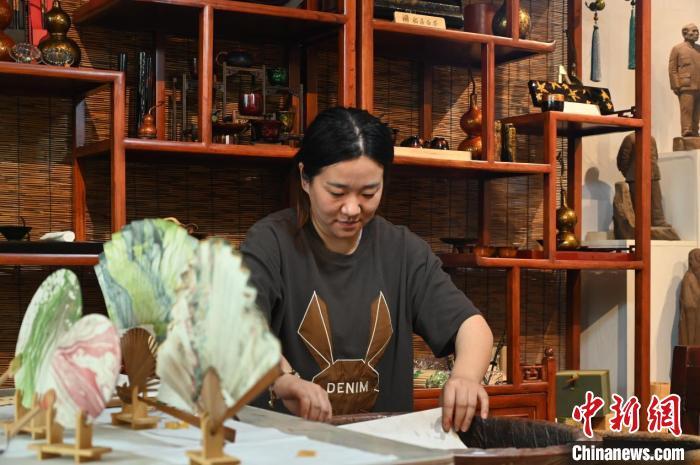 4月18日,漂漆扇制作,张曼瑜用宣纸清理水中残留色漆。张俊杰 摄