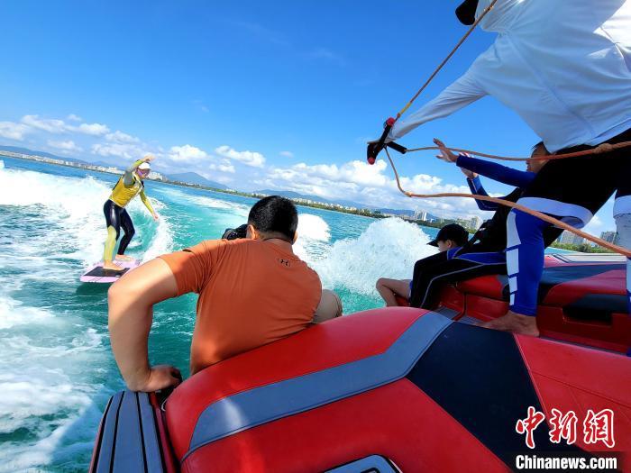 海南三亚，游客在造浪艇后进行尾波冲浪。　(资料图) 中新社记者 王晓斌 摄