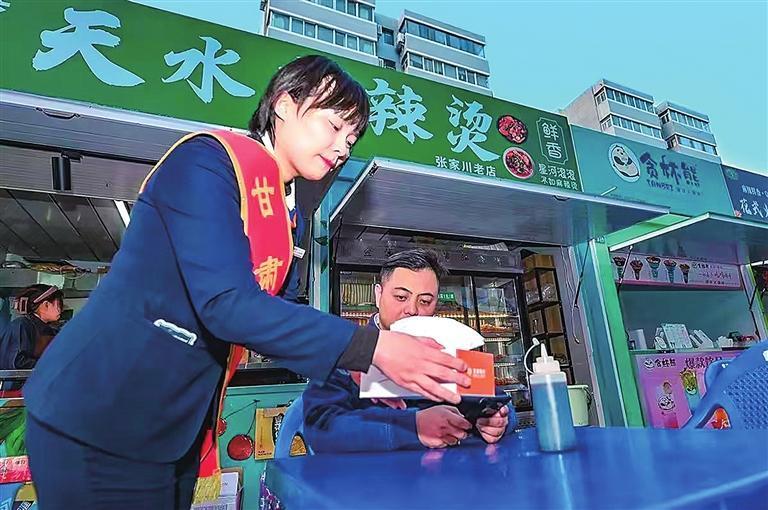 甘肃银行天水分行员工为商户免费提供纸巾，公益助力麻辣烫产业。