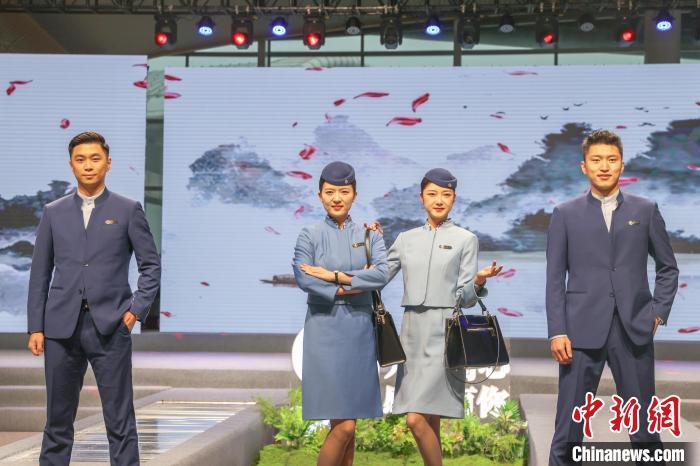 图为江西航空空乘人员身着新版制服进行走秀展示。产品包含女乘务员连衣裙、外套、围裙、帽子、大衣，男乘务员衬衫、马甲、西服外套、西裤及大衣10个品类。刘力鑫摄